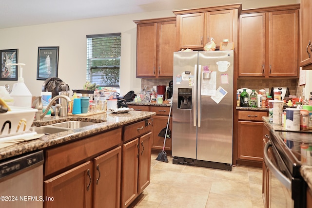 kitchen featuring stainless steel appliances, light stone counters, sink, light tile patterned floors, and backsplash