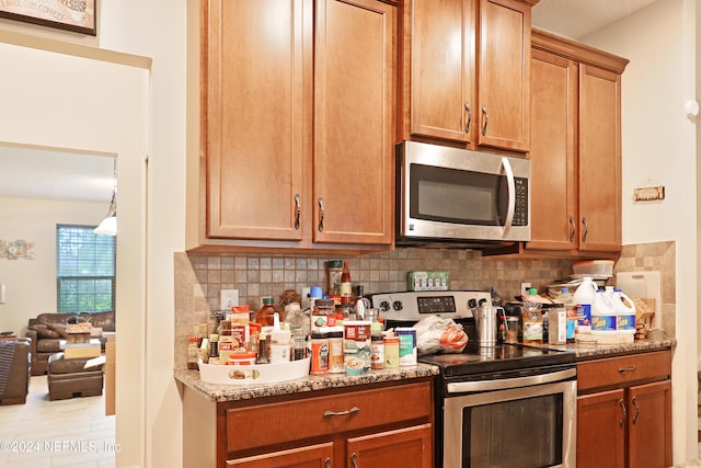 kitchen featuring stainless steel appliances, stone countertops, and decorative backsplash