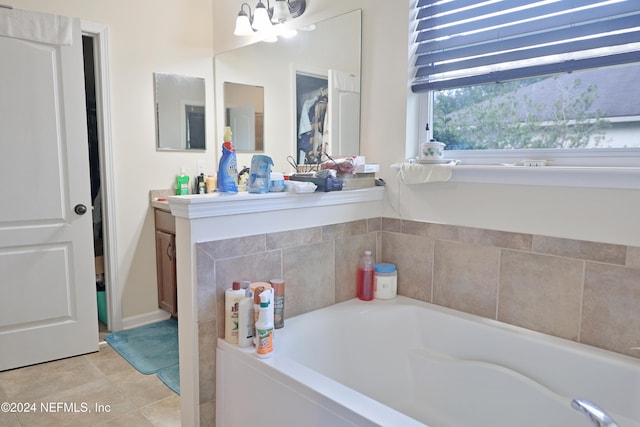 bathroom featuring tile patterned flooring, vanity, a chandelier, and a tub