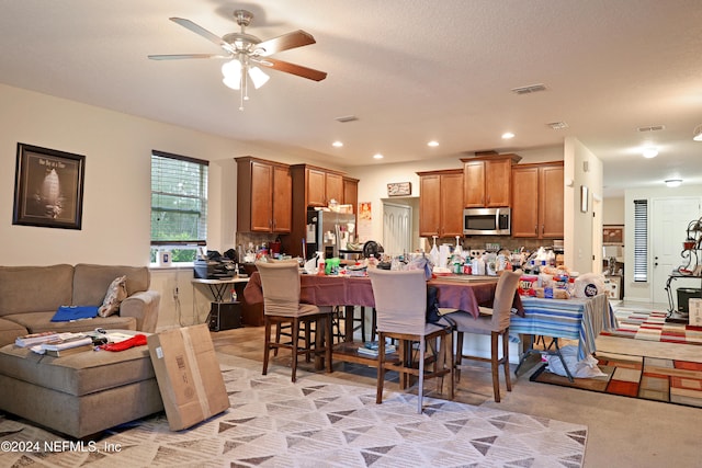 kitchen with stainless steel appliances, ceiling fan, a breakfast bar area, backsplash, and light colored carpet