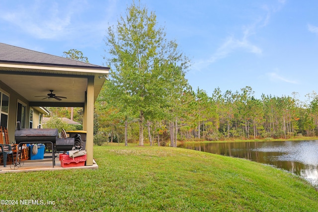 view of yard featuring a water view, ceiling fan, and a patio area