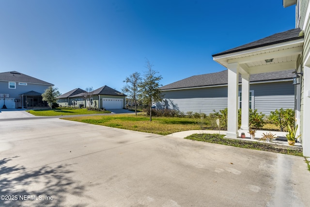 exterior space with a garage, a residential view, and a lawn