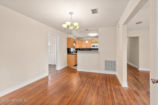 kitchen featuring a notable chandelier, hardwood / wood-style flooring, decorative backsplash, and hanging light fixtures