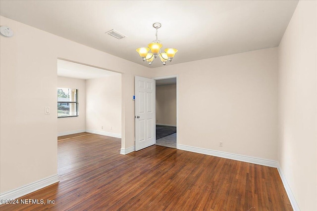 unfurnished room featuring a notable chandelier and dark hardwood / wood-style floors