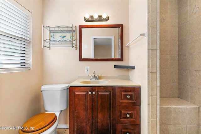 bathroom featuring vanity, toilet, and a tile shower