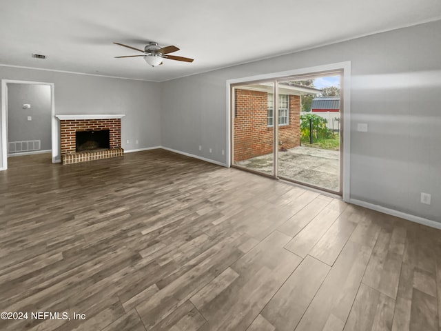 unfurnished living room featuring ornamental molding, hardwood / wood-style flooring, ceiling fan, and a brick fireplace