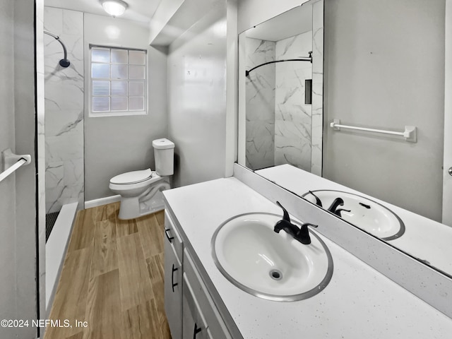 bathroom with vanity, wood-type flooring, toilet, and tiled shower