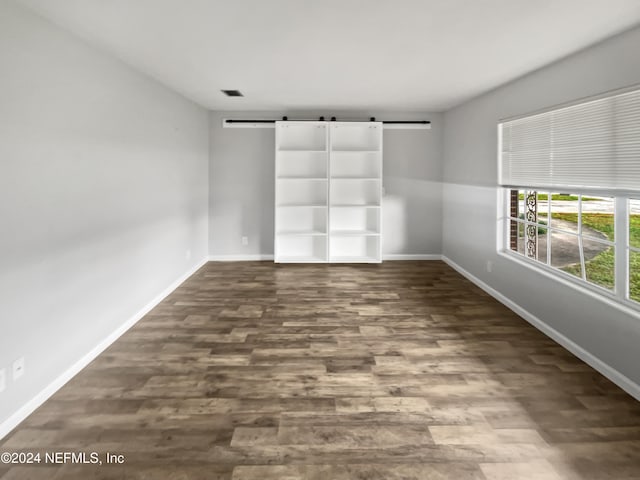 unfurnished room with dark wood-type flooring and a barn door