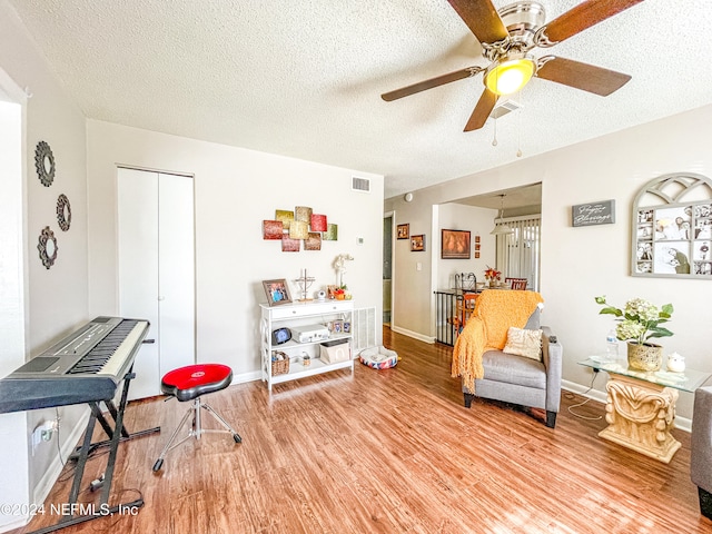 living area featuring hardwood / wood-style floors, a textured ceiling, and ceiling fan