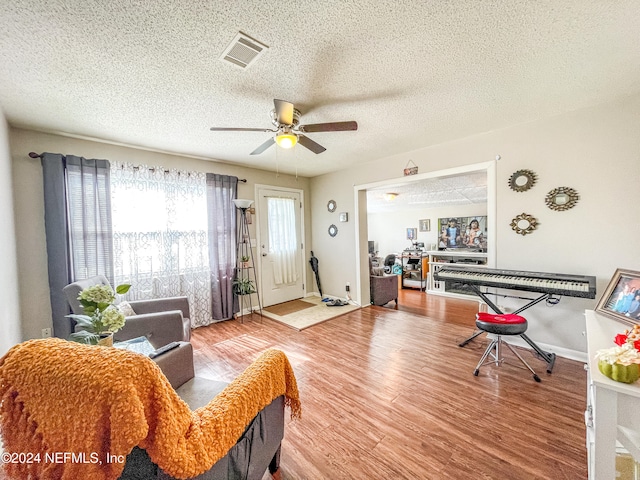 living room with wood-type flooring, a textured ceiling, and ceiling fan