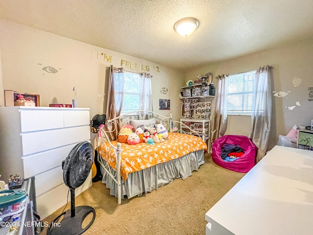 bedroom with multiple windows, a textured ceiling, and carpet floors