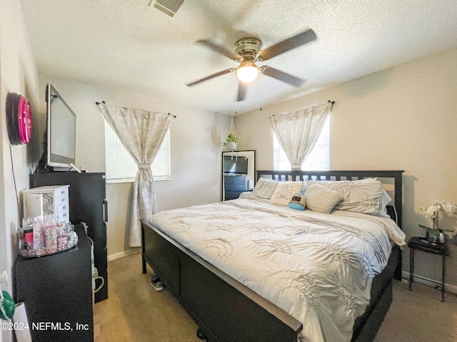 carpeted bedroom featuring ceiling fan and a textured ceiling