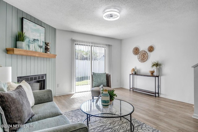 living room featuring a fireplace, a textured ceiling, and light wood-type flooring