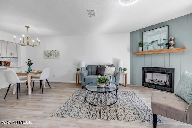 8300 Plaza Gate Ln Unit 1183, Jacksonville, FL 32217 - living room featuring a chandelier, light wood-style floors, a large fireplace, a textured ceiling, and baseboards
