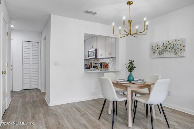 dining space with light wood-type flooring and a notable chandelier