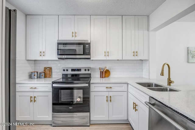 8300 Plaza Gate Ln Unit 1183, Jacksonville, FL 32217 - kitchen featuring stainless steel appliances, a sink, light stone countertops, white cabinets, and a textured ceiling