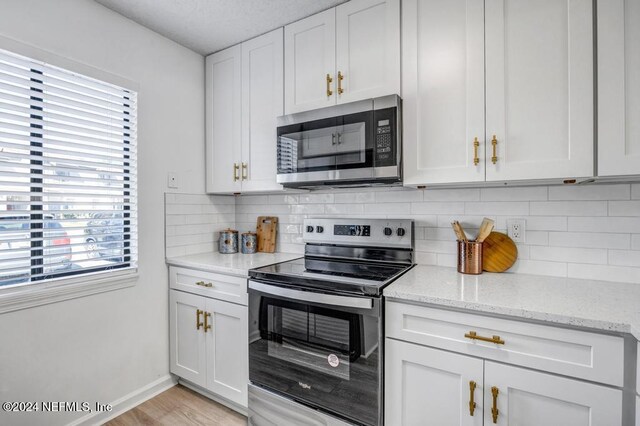 8300 Plaza Gate Ln Unit 1183, Jacksonville, FL 32217 - kitchen with appliances with stainless steel finishes, backsplash, light stone countertops, white cabinetry, and a textured ceiling