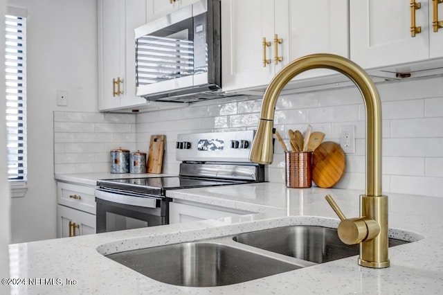 kitchen featuring stainless steel appliances, white cabinets, backsplash, and light stone counters