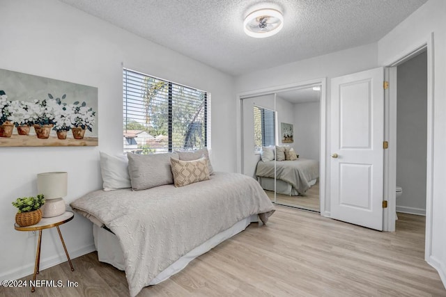 bedroom featuring light wood-type flooring, a textured ceiling, and a closet