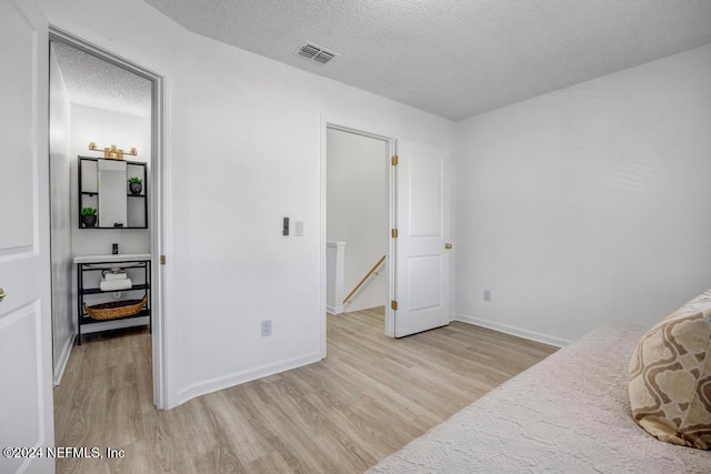 bedroom featuring a textured ceiling and light hardwood / wood-style flooring