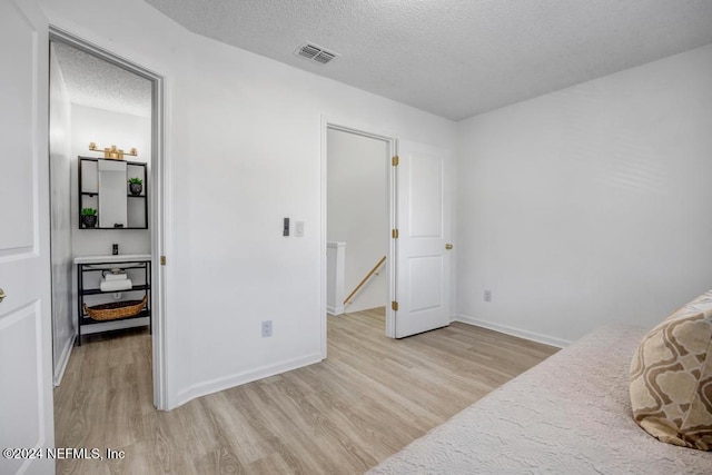8300 Plaza Gate Ln Unit 1183, Jacksonville, FL 32217 - bedroom featuring light wood-style flooring, a textured ceiling, and baseboards