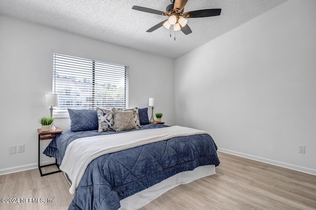 bedroom with light wood-type flooring, a textured ceiling, and ceiling fan