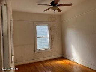 empty room with hardwood / wood-style floors and ceiling fan