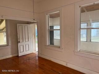 empty room with a healthy amount of sunlight and dark hardwood / wood-style floors