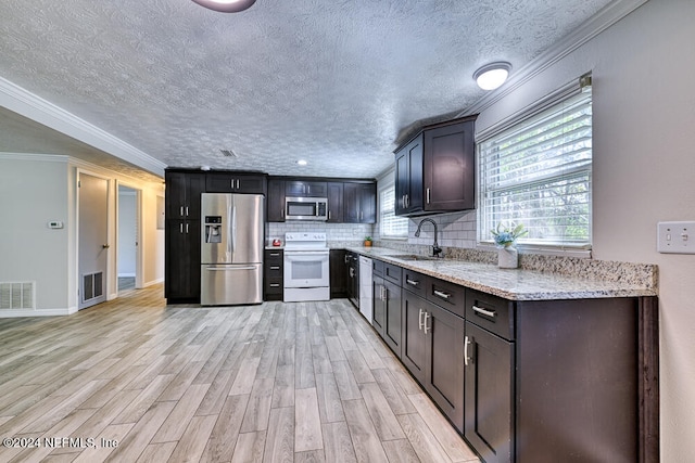 kitchen with light hardwood / wood-style flooring, ornamental molding, sink, light stone countertops, and appliances with stainless steel finishes