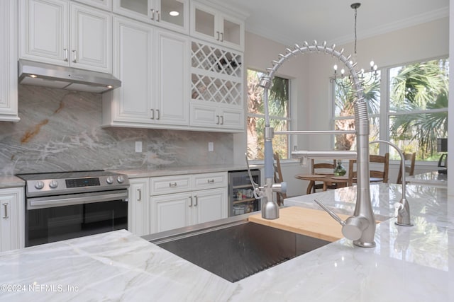 kitchen featuring stainless steel electric stove, a healthy amount of sunlight, light stone countertops, and white cabinets