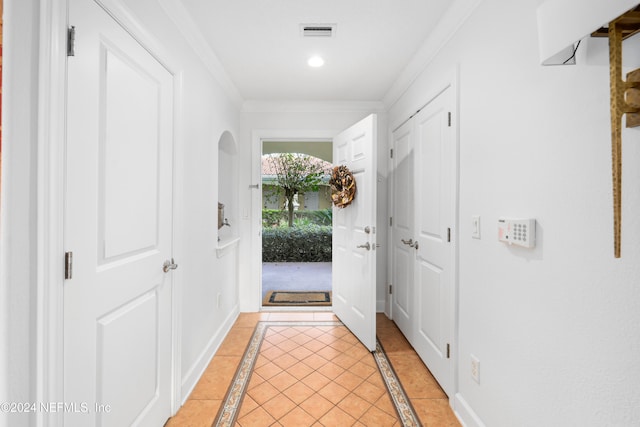 doorway to outside with crown molding and light tile patterned floors