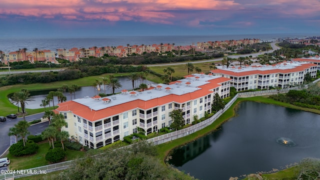 aerial view at dusk featuring a water view