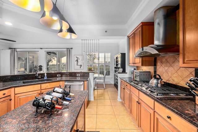 kitchen featuring stainless steel appliances, wall chimney exhaust hood, pendant lighting, dark stone countertops, and light tile patterned floors