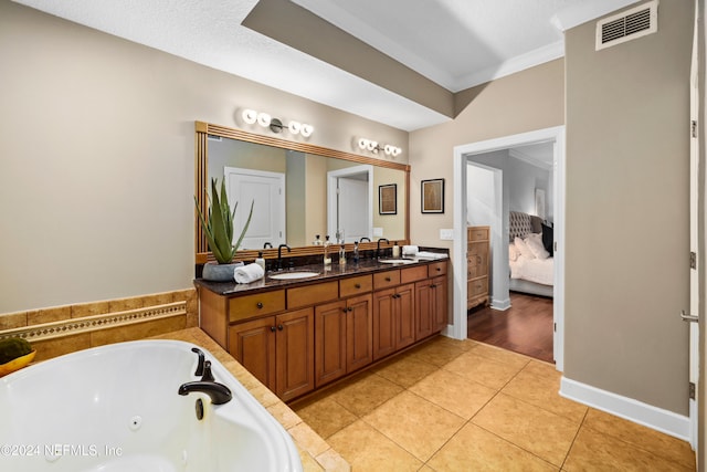 bathroom with a bathtub, a textured ceiling, ornamental molding, vanity, and tile patterned flooring