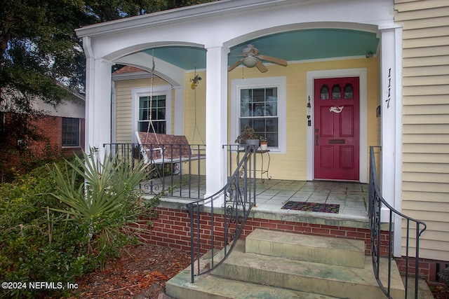 view of exterior entry with a porch and ceiling fan