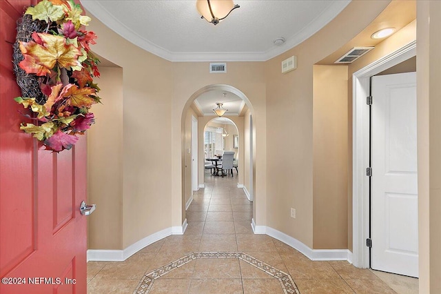 corridor with crown molding, a textured ceiling, and light tile patterned flooring