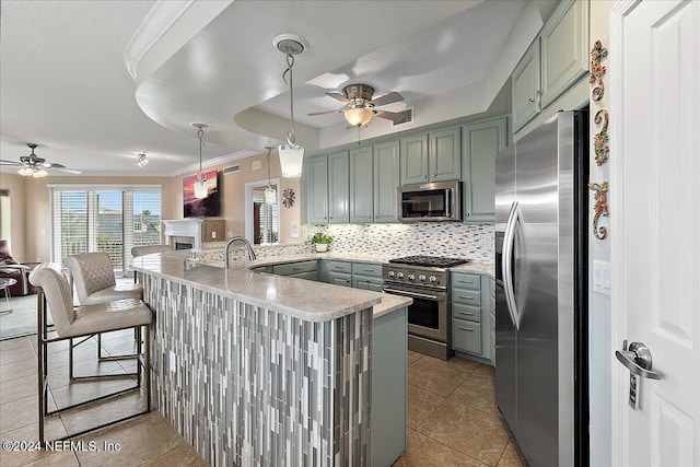 kitchen featuring kitchen peninsula, decorative backsplash, a kitchen breakfast bar, stainless steel appliances, and ornamental molding