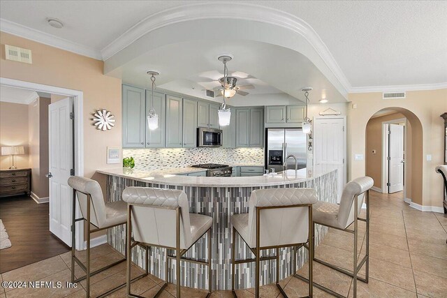 kitchen featuring crown molding, kitchen peninsula, appliances with stainless steel finishes, and light wood-type flooring