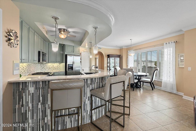 kitchen with kitchen peninsula, a breakfast bar, stainless steel appliances, sink, and green cabinets