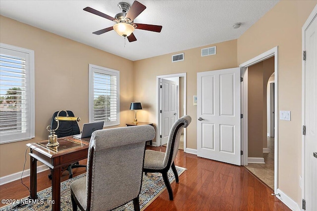 office featuring hardwood / wood-style floors, a healthy amount of sunlight, a textured ceiling, and ceiling fan