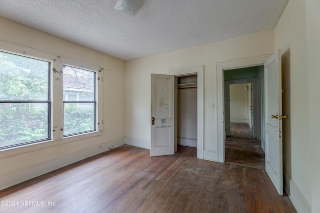 unfurnished bedroom with a closet, a textured ceiling, and dark hardwood / wood-style flooring