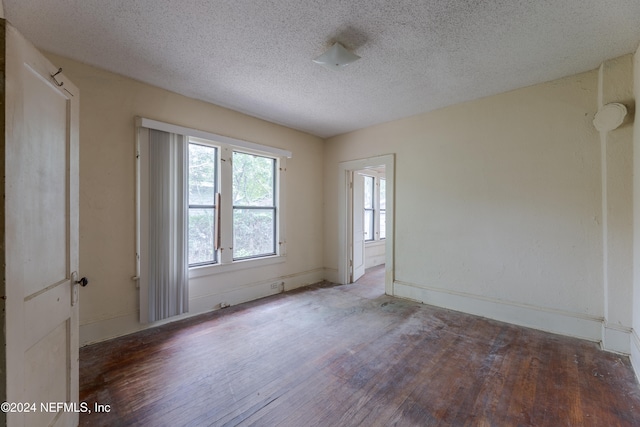 unfurnished room with a textured ceiling and dark hardwood / wood-style floors