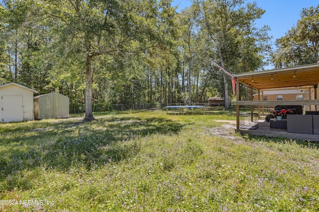 view of yard with a wooden deck, a storage shed, and a trampoline