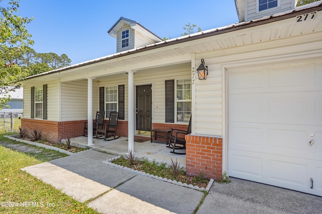 view of exterior entry with a garage and a porch