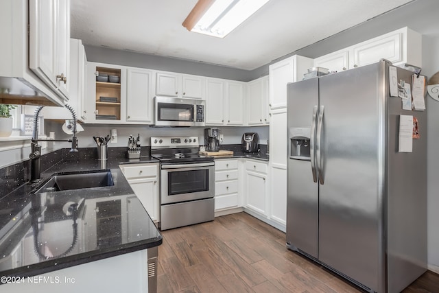 kitchen with appliances with stainless steel finishes, dark hardwood / wood-style floors, white cabinetry, and dark stone counters