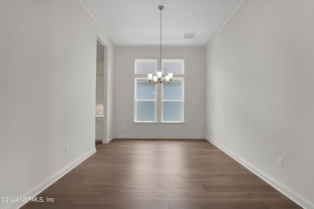 unfurnished dining area with ornamental molding, a notable chandelier, and dark hardwood / wood-style floors