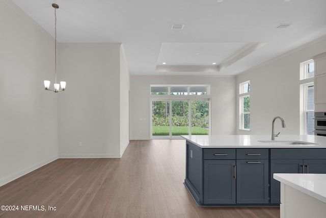 kitchen featuring sink, light wood-type flooring, an inviting chandelier, and hanging light fixtures