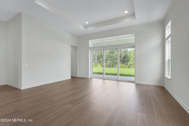 spare room featuring ornamental molding, hardwood / wood-style floors, a tray ceiling, and a high ceiling