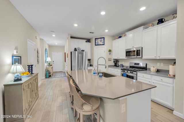 kitchen featuring sink, appliances with stainless steel finishes, an island with sink, and white cabinetry