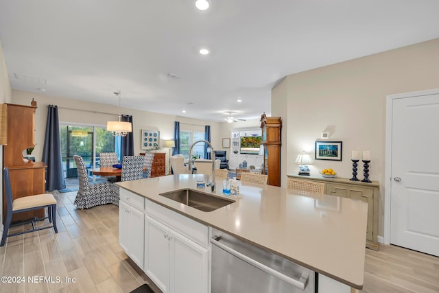 kitchen featuring a center island with sink, hanging light fixtures, stainless steel dishwasher, white cabinets, and sink